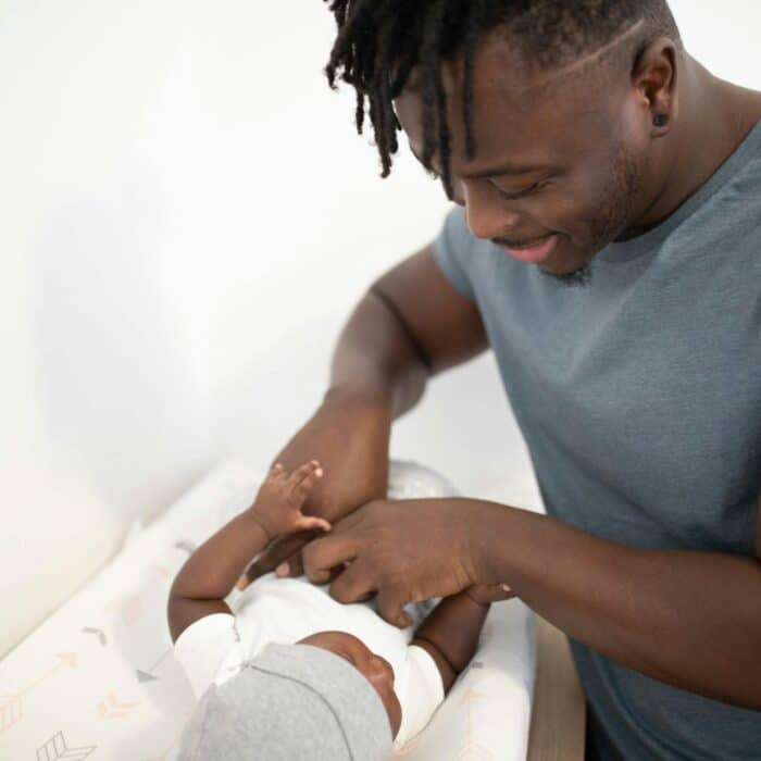 Loving father joyfully interacts with baby during diaper change.